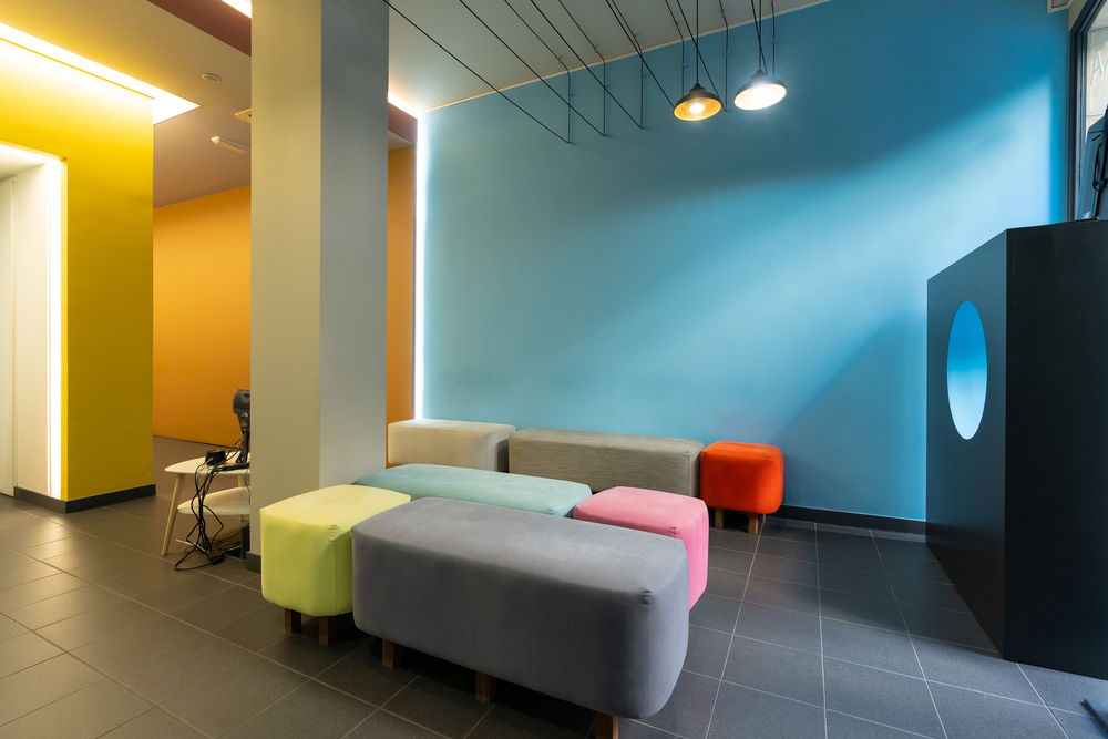 Sala moderna con taburetes en tonos pastel y paredes en colores vivos, ideal para explorar combinaciones de muebles y contrastes cromáticos.